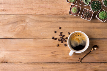 coffee cup with cactus on the wooden background with copy space, top view