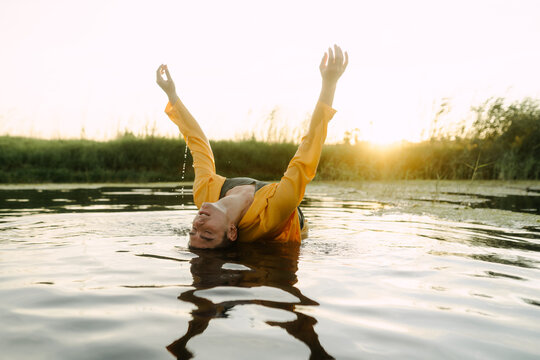 Clothed man bending backward on a lake