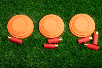 Clay disc flying targets and shotgun bullets on green grass background ,Clay Pigeon target