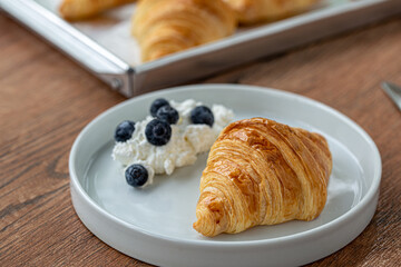 Delicious breakfast with fresh croissants with blueberry and cream on breakfast table.