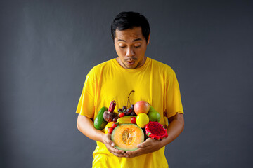 Shocked Asian man holding assorted fresh fruits for healthy life style concept