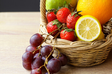 Assorted fresh fruits in basket on wooden table