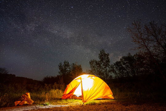 The milky way floats over a tent on the prairies.