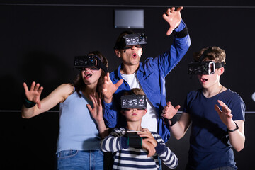Positive family with children playfully poses in virtual reality glasses