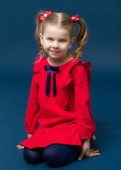 Charming little girl in red dress sitting on knees