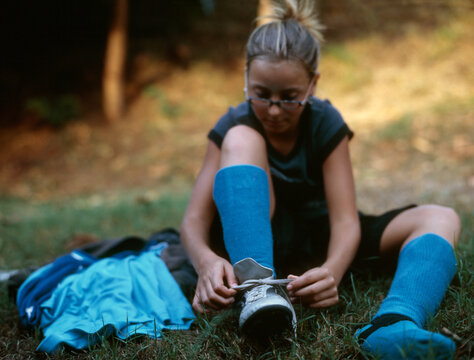 Girl crouching while tying shoelace 