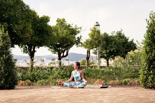 Asian yogi in lotus pose in garden.
