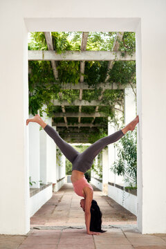 Woman performing handstand in archway
