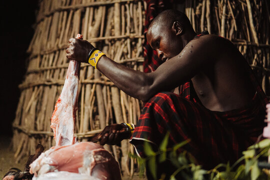 Masai man cutting a dead goat
