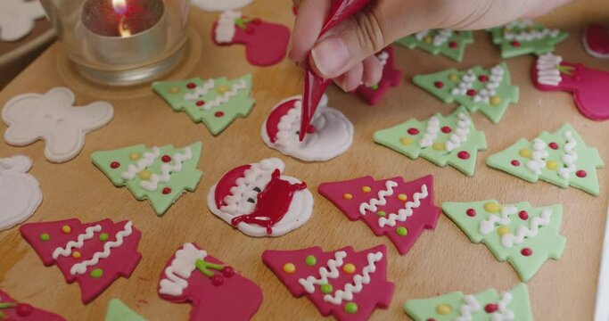 Close-up hand making craft gift Xmas snack cooking on table in good warm relax time. Cute smile gingerman mold shape wear royal icing sugar glaze face with red green color for Covid-19 Coronavirus.