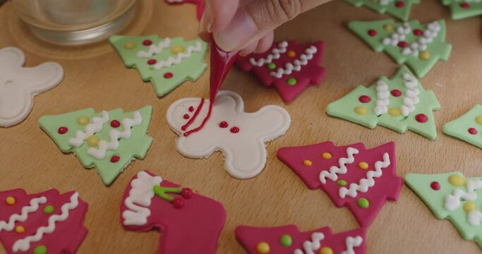 Close-up hand making craft gift Xmas snack cooking on table in good warm relax time. Cute smile gingerman mold shape wear royal icing sugar glaze face with red green color for Covid-19 Coronavirus.