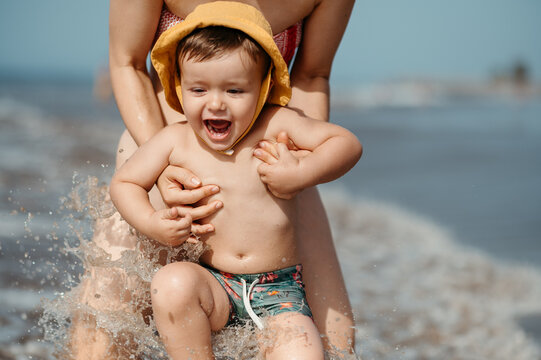 Mommy playing with son on beach.