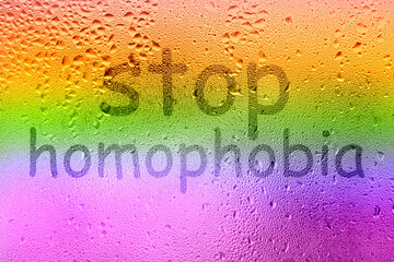 The inscription on the sweaty glass. The word STOP HOMOPHOBIA written on glass with rainbow