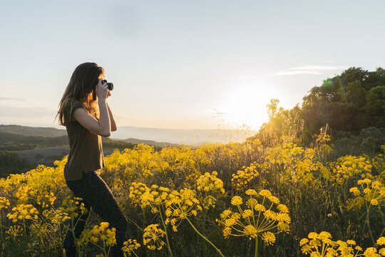 Young woman taking photos in mountain at sunset