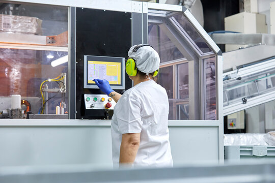 Factory worker operating machine on plant