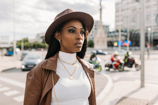 Serious black woman in leather coat and hat