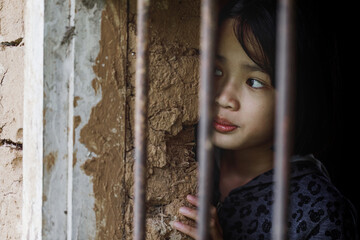 Little girl stressed trapped in the steel cage. Human trafficking or violence against women and children concept.