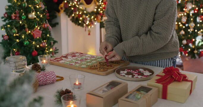 Asia happy adult people woman enjoy make craft gift for Xmas eve party snack cooking food recipe on kitchen table in good warm time. Cute smile gingerman bakery icing sugar with red green white color.