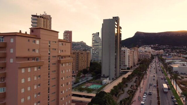 Drone clip flying over traffic and luxurious hotels during sunset in the city of Calpe in Spain