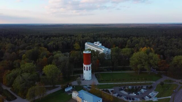 Kemeri Water Tower With Latvian Flag in the Kemeri Resort Park in Jurmala, Latvia. Beautiful White Neoclassicism Architecture House in Background. Aerial View From Above. Colorfull  Autumn Evening