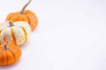 A view of three small pumpkins on a white background, on the left side of the frame.