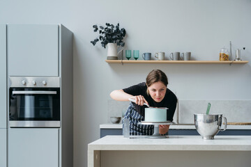 A female pastry chef makes a cake.
