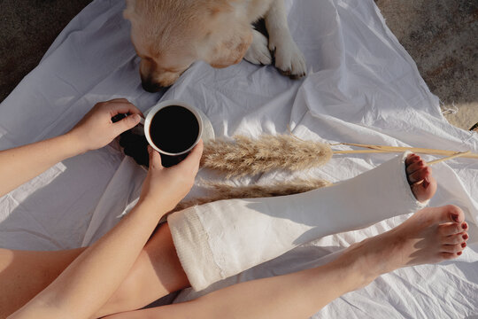 Woman With Broken Leg Holding Cup Of Coffee 