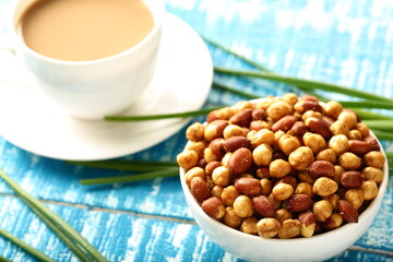 Organic salt4d and roasted peanuts served with cup of milk tea.