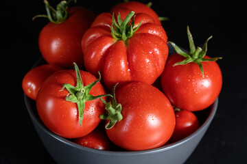 Ripe raw red tomatoes with water drops in a bowl 
