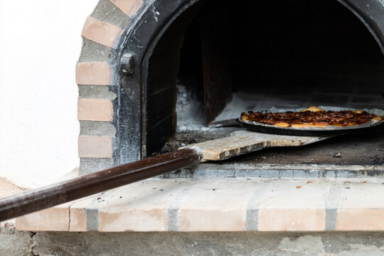Pizza made in a white painted artisan wood oven built on the outside
