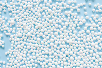 Abstract background consisting of spheres of white color on blue paper top view. Minimal arrangement of small circles.