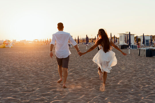Couple running away hand by hand on the beach