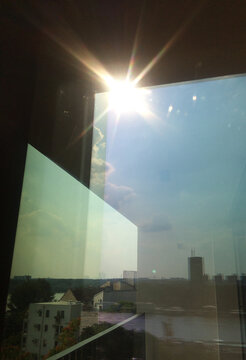 window view of the sun, city and sky