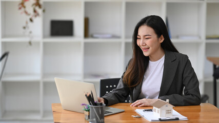 Attractive businesswoman sitting in modern office and using laptop computer.