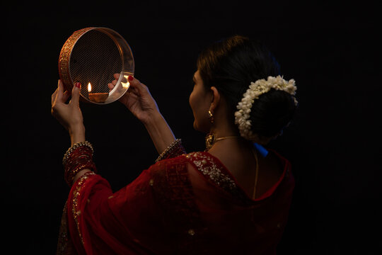 Woman looking at moon through a sieve during Karva Chauth