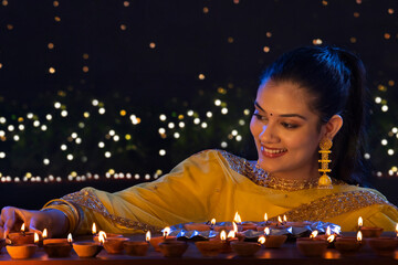 Beautiful Indian girl placing diyas with smile on the occasion of Diwali