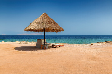 Sun umbrella and beach chairs in Sunny beach in tropical resort in in coral reef in Red Sea coast