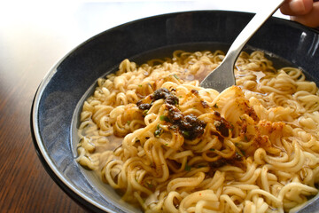 Instant noodles in a blue bowl.  Noodles with seasoning on fork. 
