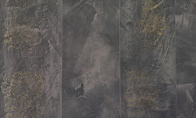 Black or dark grey background in abstract style. Black Venetian plaster with gold printed patterns, a pattern of gold flowers against a black stone wall background. Texture of black plaster in Venice