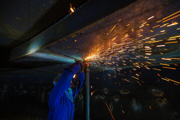 Male worker  grinding on steel plate with flash of sparks close up wear protective gloves