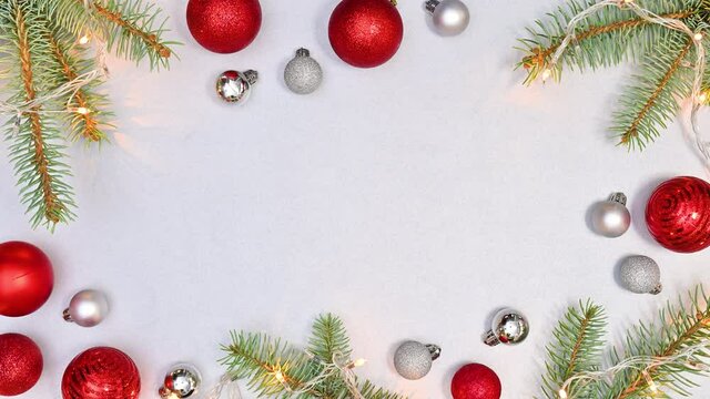 Blinking Christmas lights on natural fir twigs with red and silver ornaments on silver theme. Stop motion