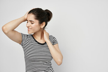 woman in a striped t-shirt pain in the neck light background