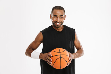 Young black sportsman smiling at camera while posing with basketball