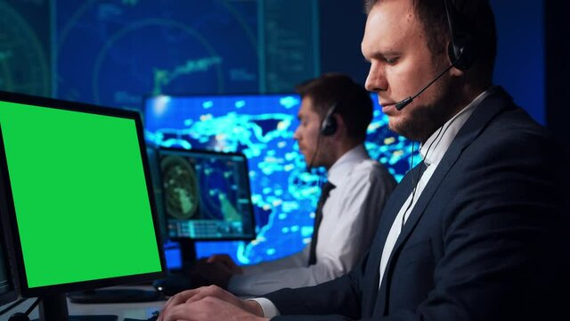 Workplace of the air traffic controllers in the control tower. Diverse team of professional aircraft control officers works using radar, computer navigation and digital maps. Chroma key green display.