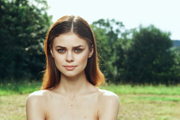 smiling woman in a field outdoors bare shoulders clear skin model