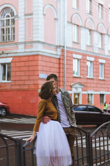 Love story of stylish funny couple: young man in a t-shirt. And a cute young woman in wedding white skirt and yellow sweater. Family holiday and togetherness, date.