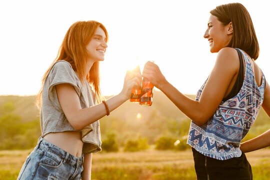 White Two Women Smiling And Drinking Soda While Hiking Outdoors