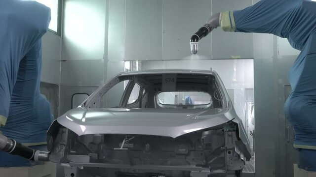 Robotic arms spray painting a vehicle body at a car manufacturing factory
