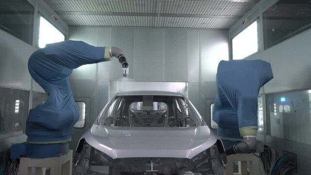 Robotic arms spray painting a vehicle body at a car manufacturing factory