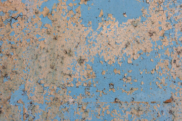 Peeling paint on the wall. Old concrete wall with cracked flaking paint. Weathered rough painted surface with patterns of cracks and peeling. Grunge texture for background and design. High resolution.